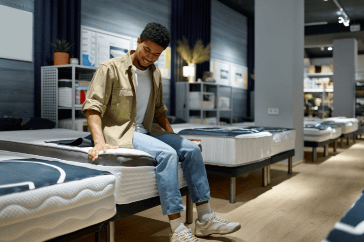 Man Choosing Mattress Sitting on a Bed in the shop