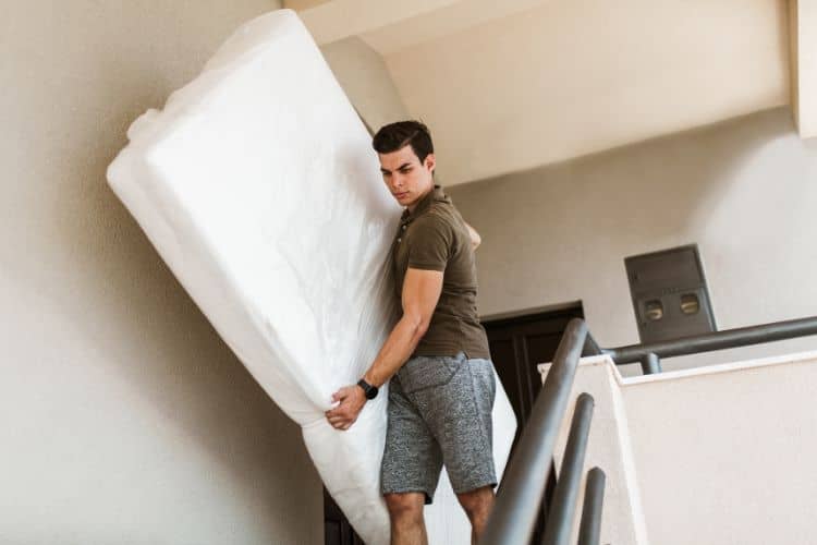 Man carrying a mattress downstairs