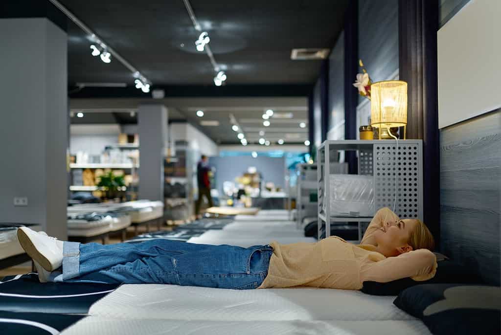 woman choosing bed mattress in furniture store