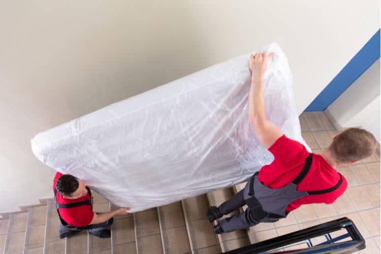 Young men carrying a wrapped mattress